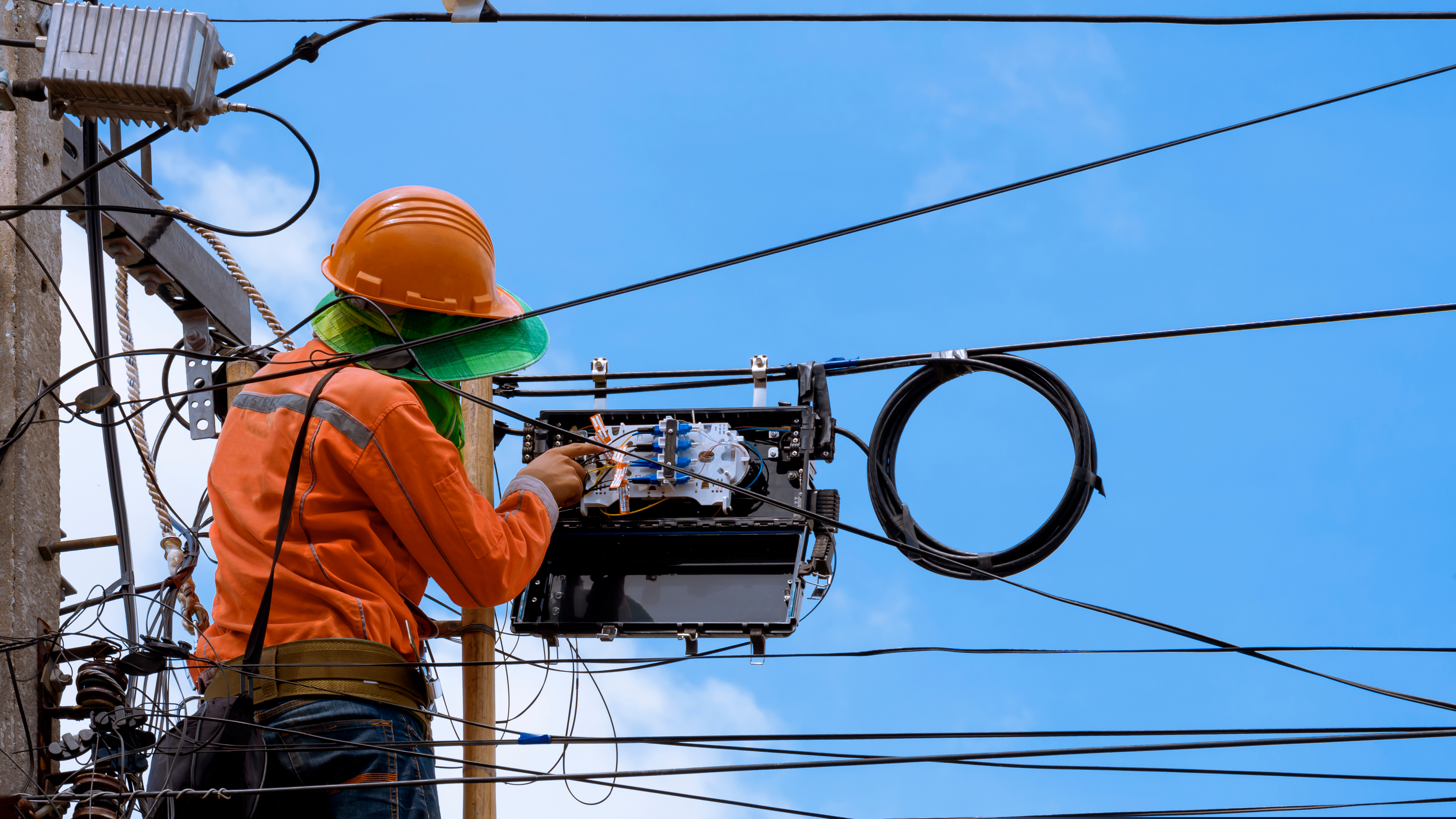 Un technicien qui raccorde la fibre optique sur un pylon