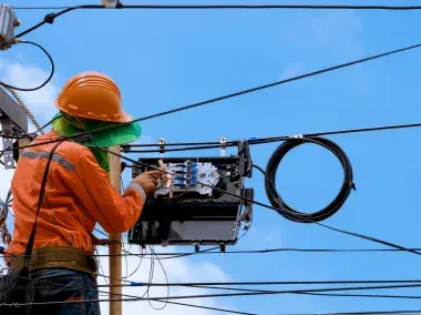 Un technicien qui raccorde la fibre optique sur un pylon